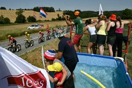 Uno-X Mobility’s Torstein Træen (second left in the yellow jersey) with the peloton riding past spectators cooling in a paddling pool